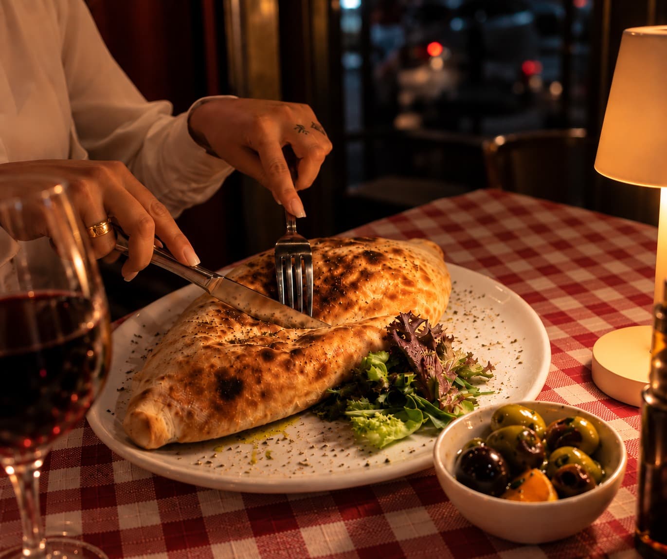 Calzone wird an einem Tisch bei Kerzenlicht aufgeschnitten